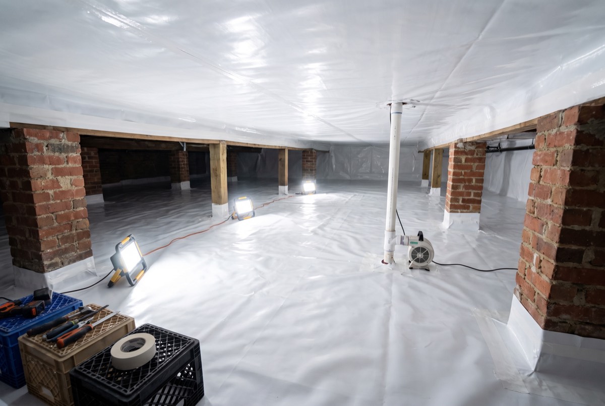 Crawl space sealed with white membrane and suction pipe for radon mitigation, Dallas TX